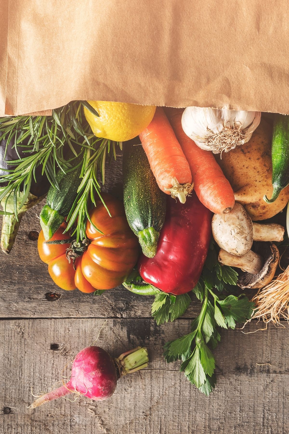 fresh produce pouring out of a paper shopping bag.