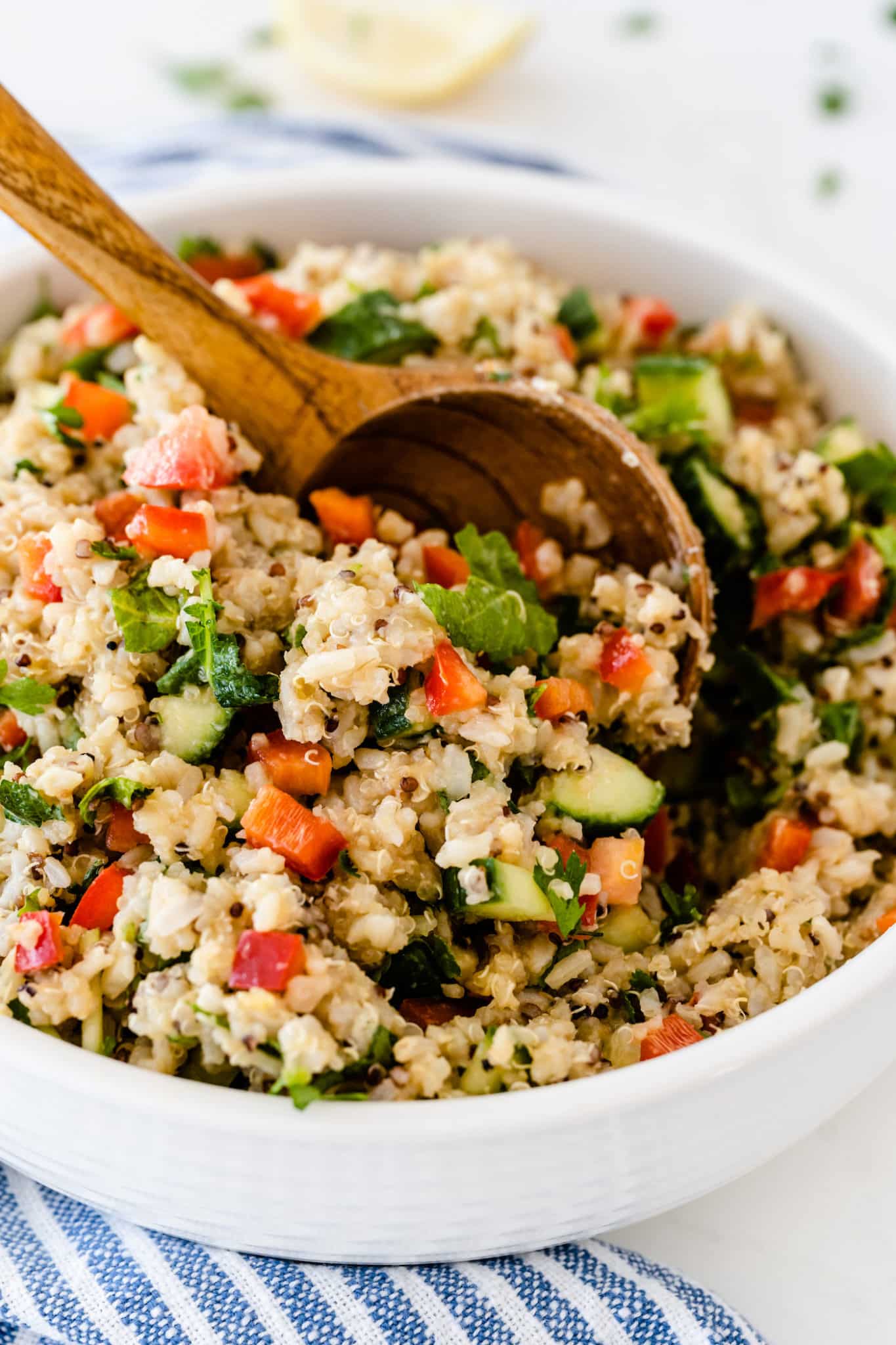 wooden spoon stirring a bowl of copycat costco quinoa salad.