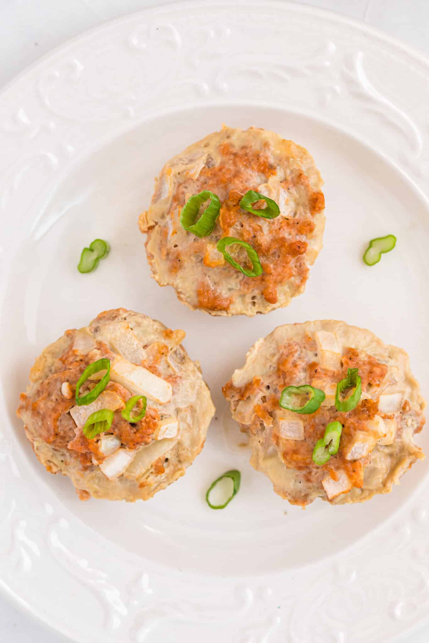 three cooked muffins on a serving plate.