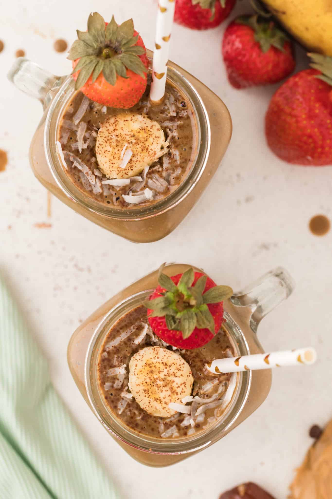 chocolate smoothie in two glasses garnished with fresh fruit and coconut