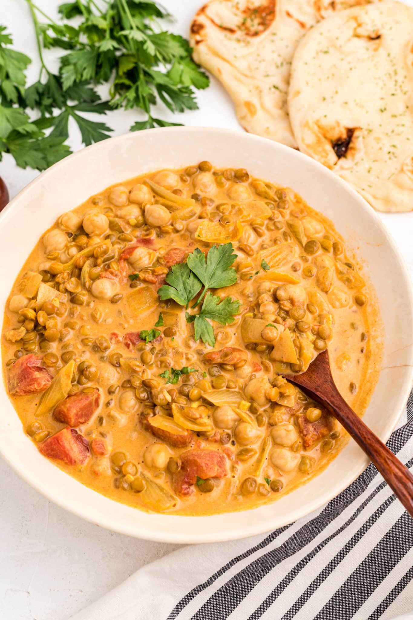 chickpea and lentil curry served in bowl with spoon.