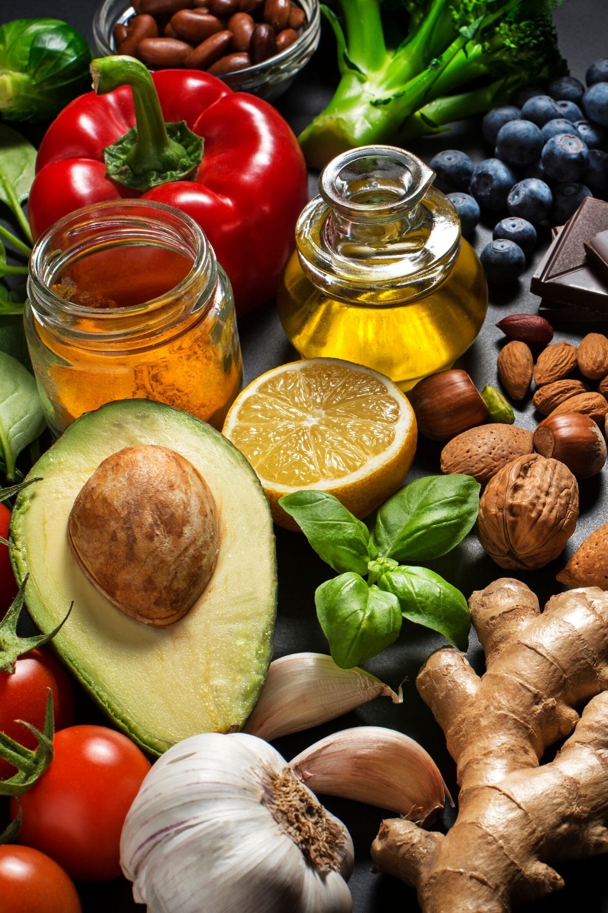 fresh foods like avocado, fruit, and nuts on a dark table