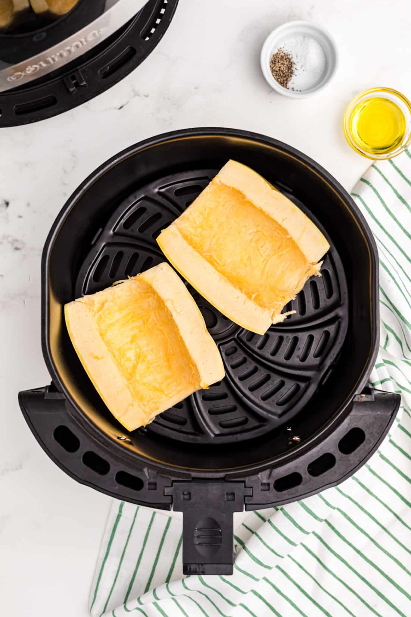 spaghetti squash halved inside air fryer basket.