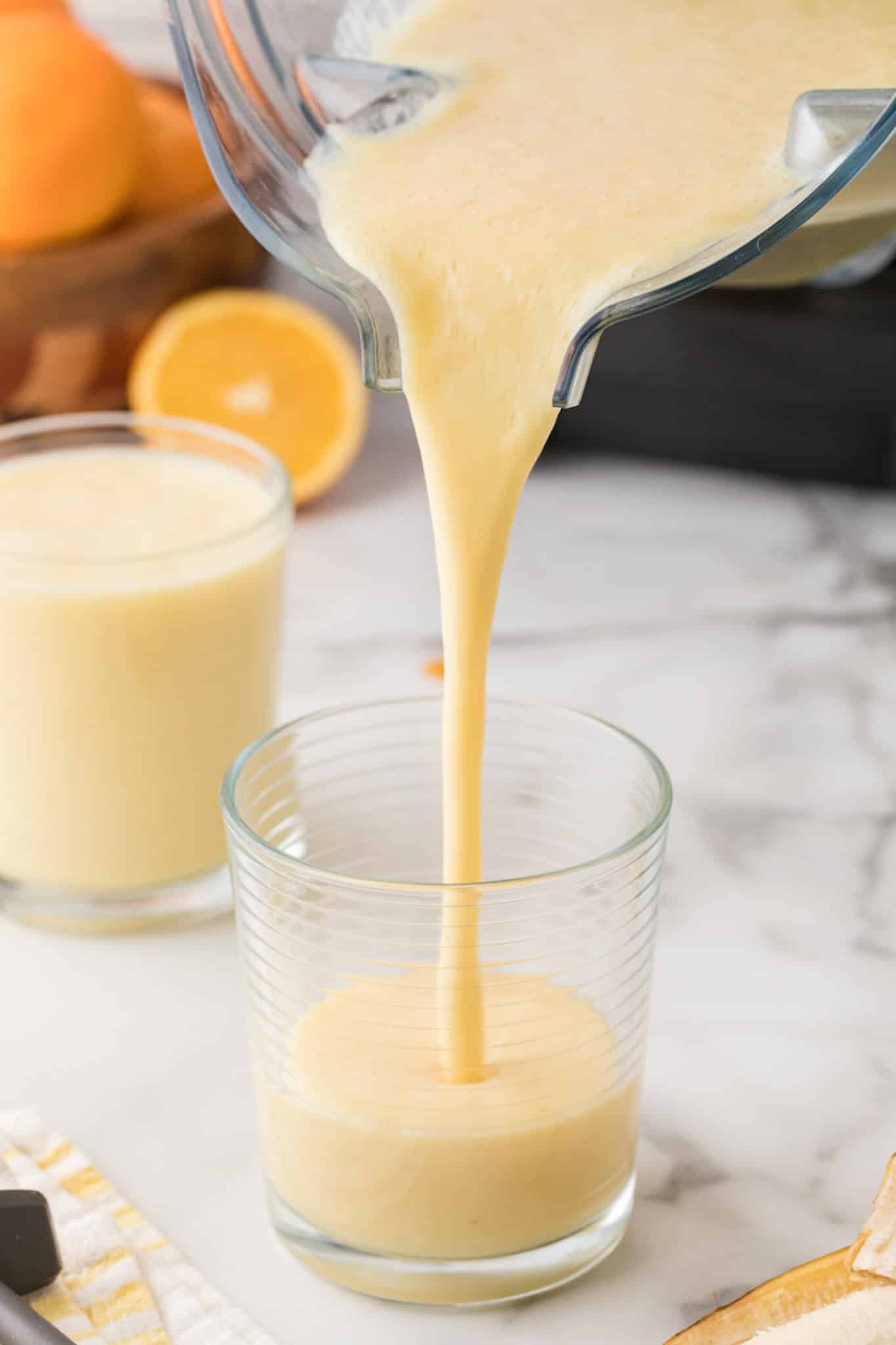 pouring orange smoothie into glass