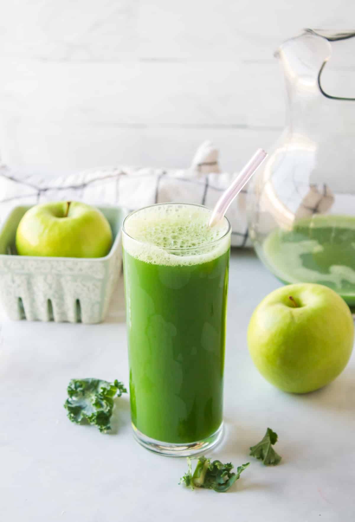 glass of green juice in clear glass with straw.