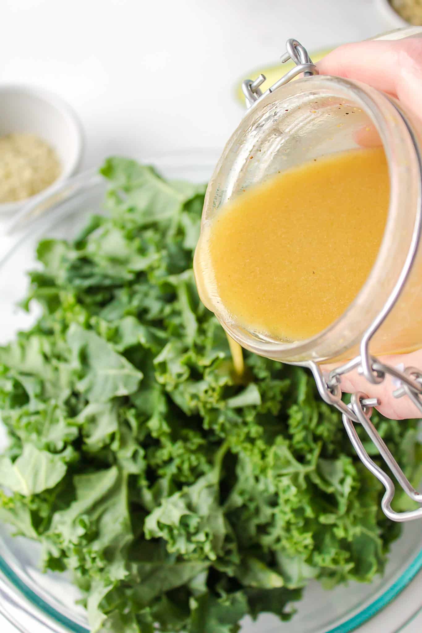 pouring salad dressing onto kale