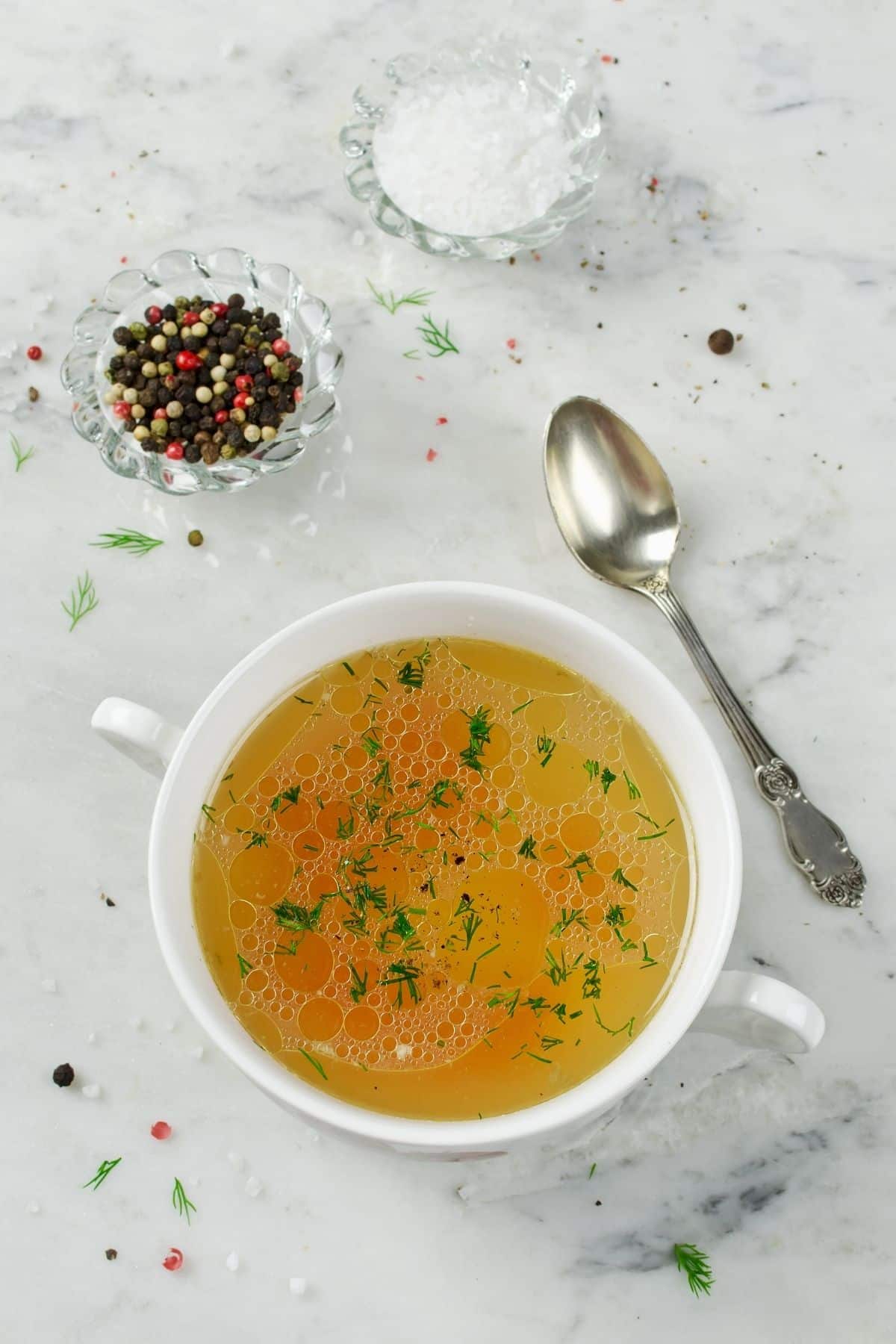 Bowl of chicken broth with a salt and pepper.