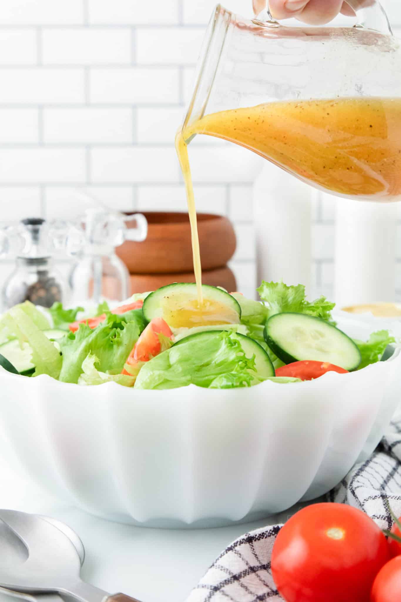 pouring honey mustard vinaigrette onto salad.