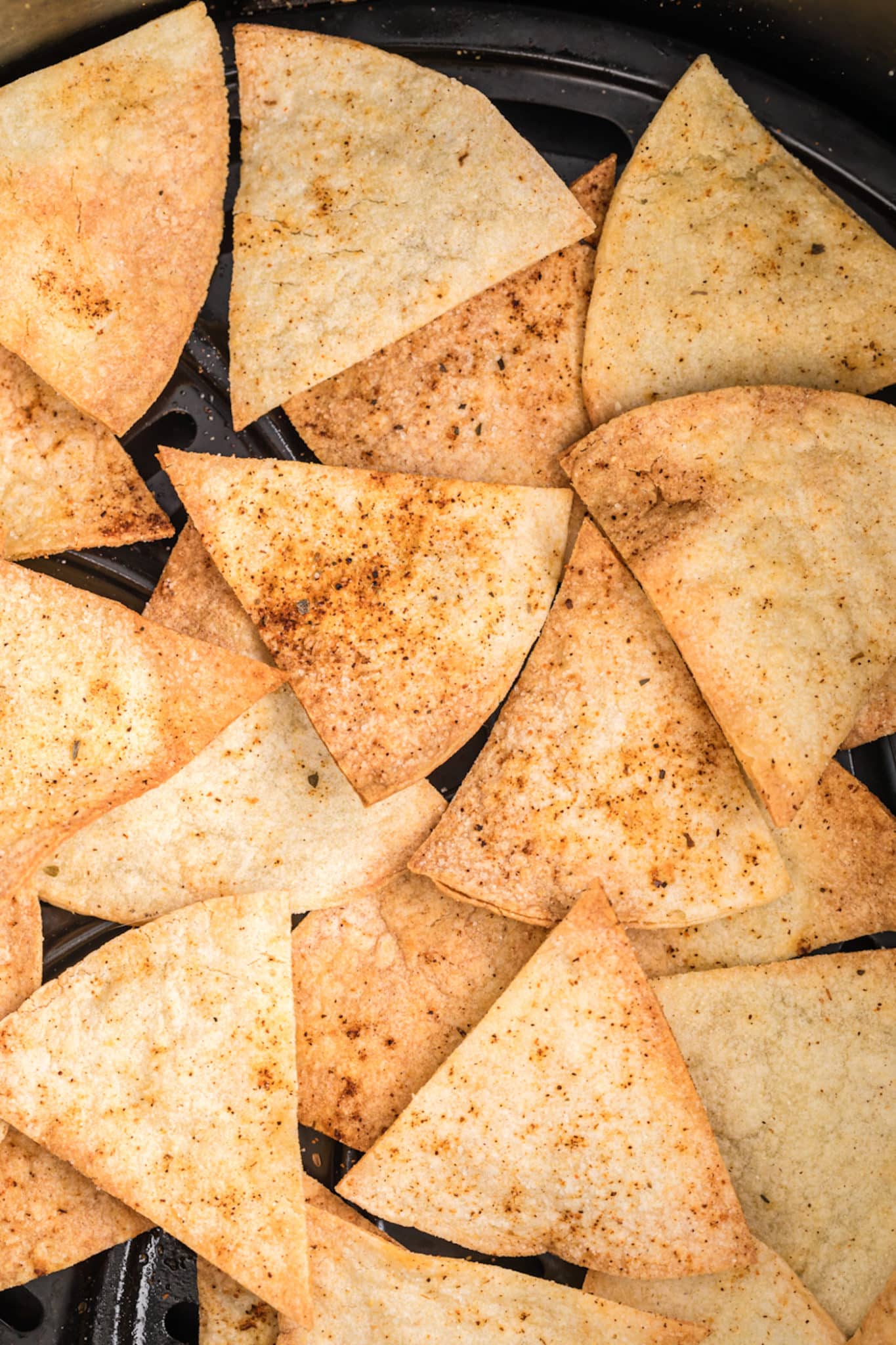 Close up of homemade corn tortilla chips in an air fryer basket.