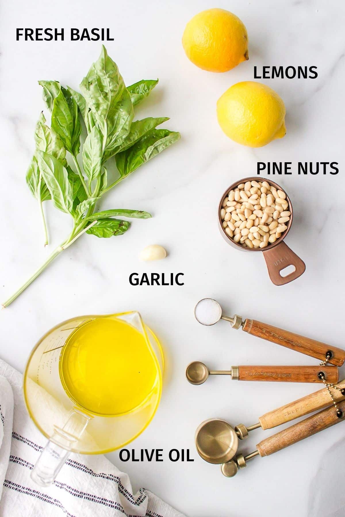 Ingredients for dairy free pesto laid out on a white surface.