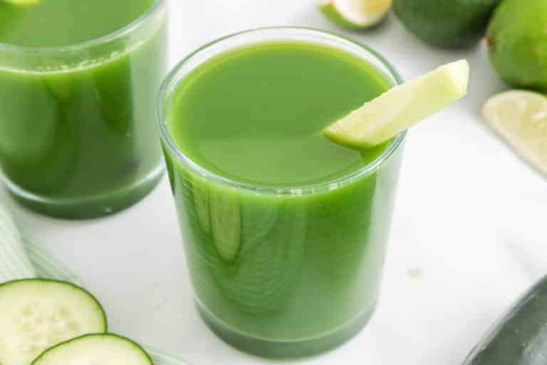 Top view of a glass of cucumber juice with a lime wedge on the rim.