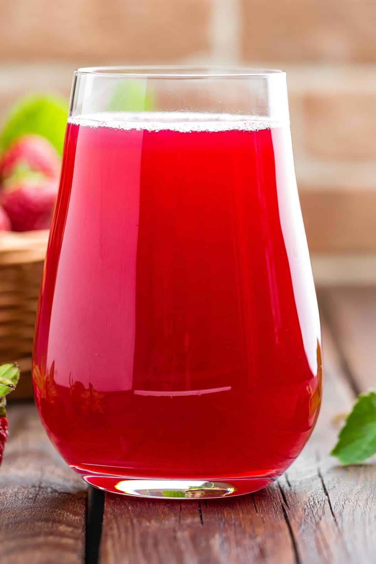 red strawberry juice served in a pretty glass on a tabletop.