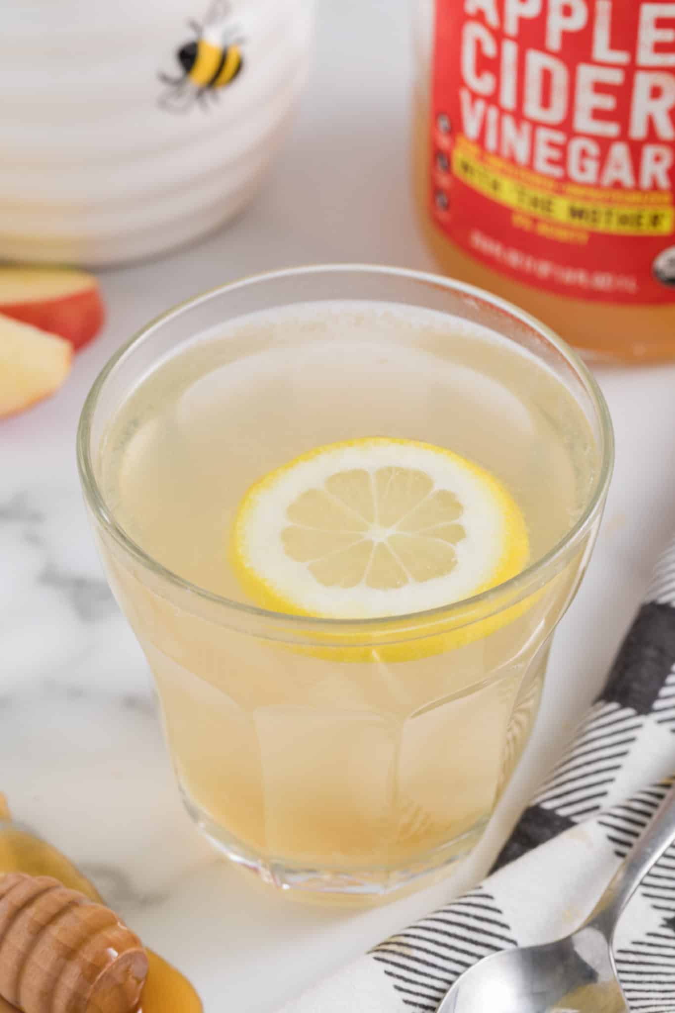 Apple cider vinegar drink in a glass with a floating lemon wheel.