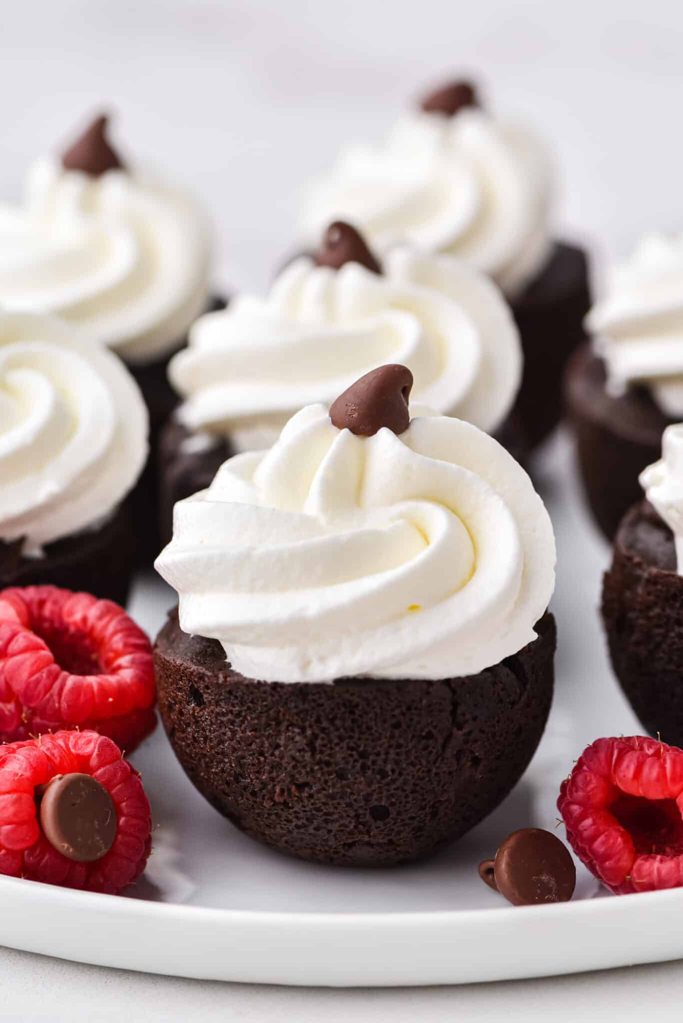 Instant Pot brownie bites topping with whipped cream on a white plate.