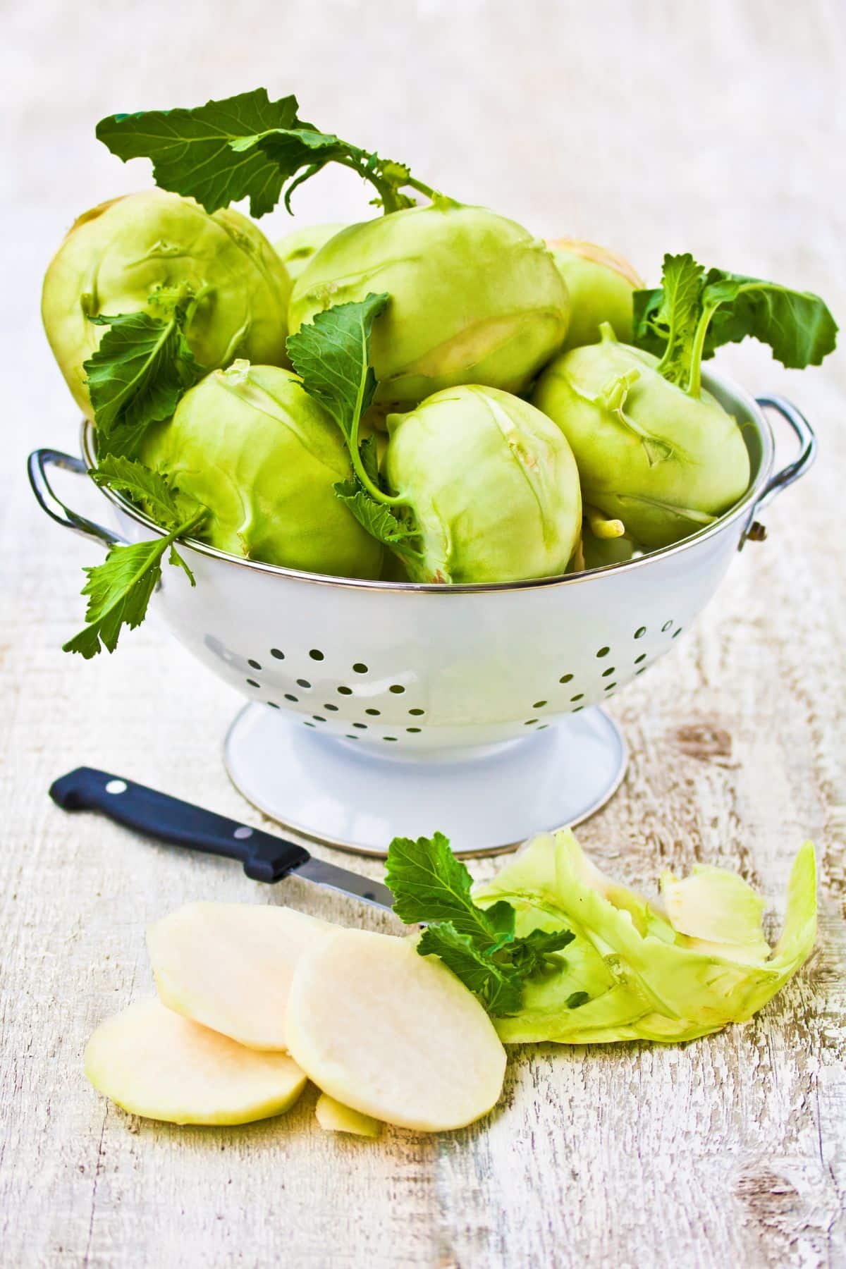 Colander with kohlrabi beside sliced kohlrabi.