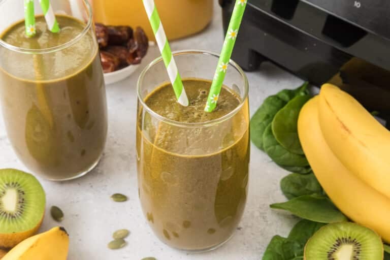 A glass of iron rich green smoothie with two green striped straws.