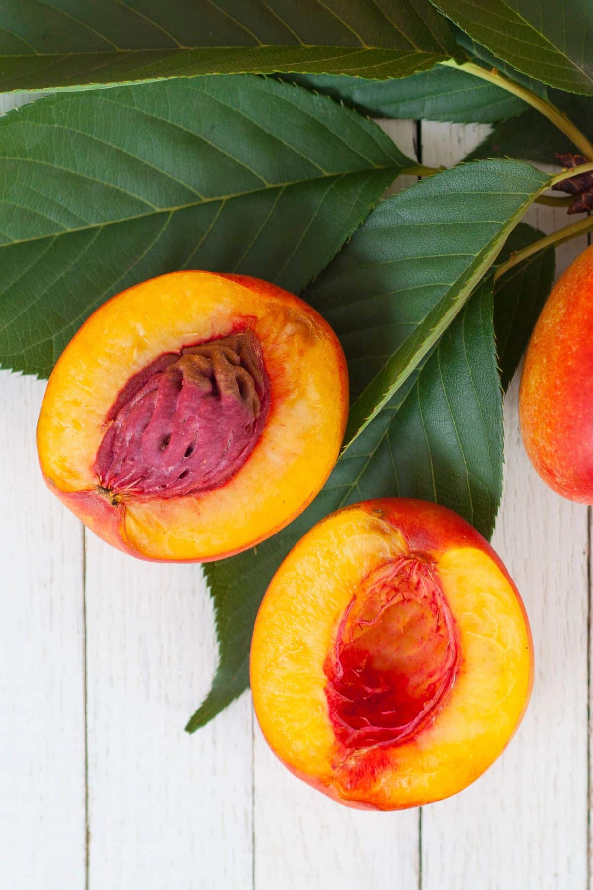 a sliced nectarine on a bed of leaves.