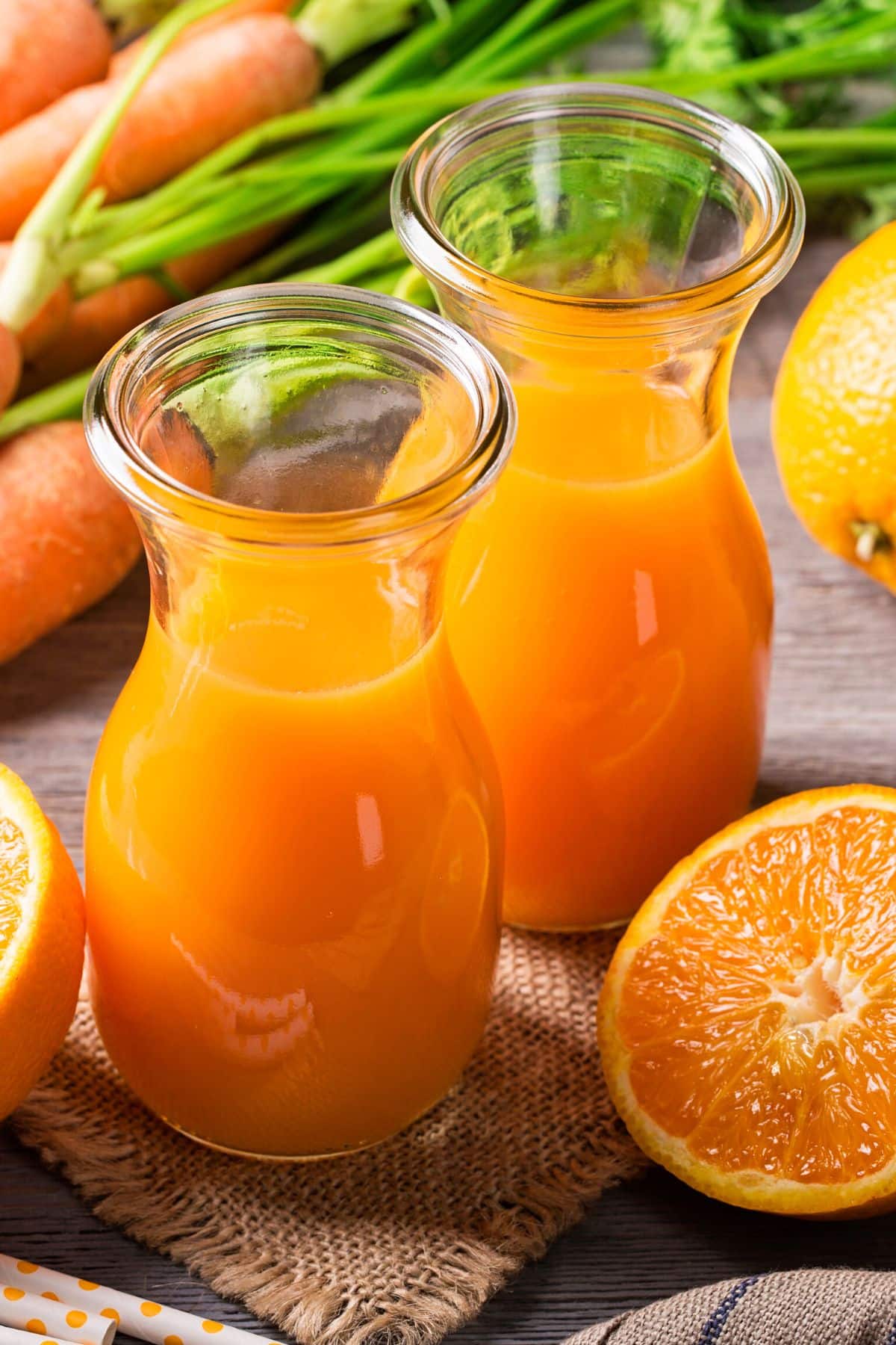 Two mini carafes of carrot mango juice on a table.