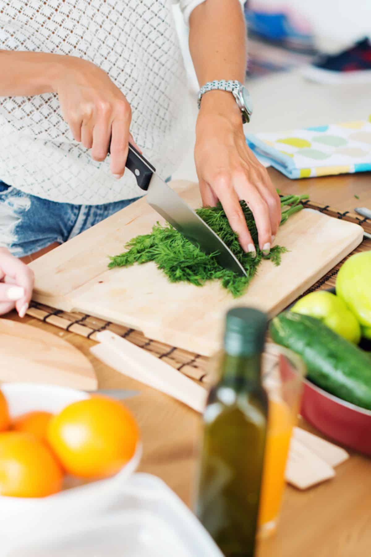 woman preparing fresh dill for salad.