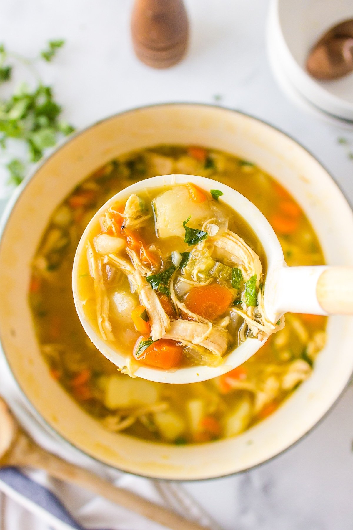 a ladle full of bone broth chicken soup over a bowl.