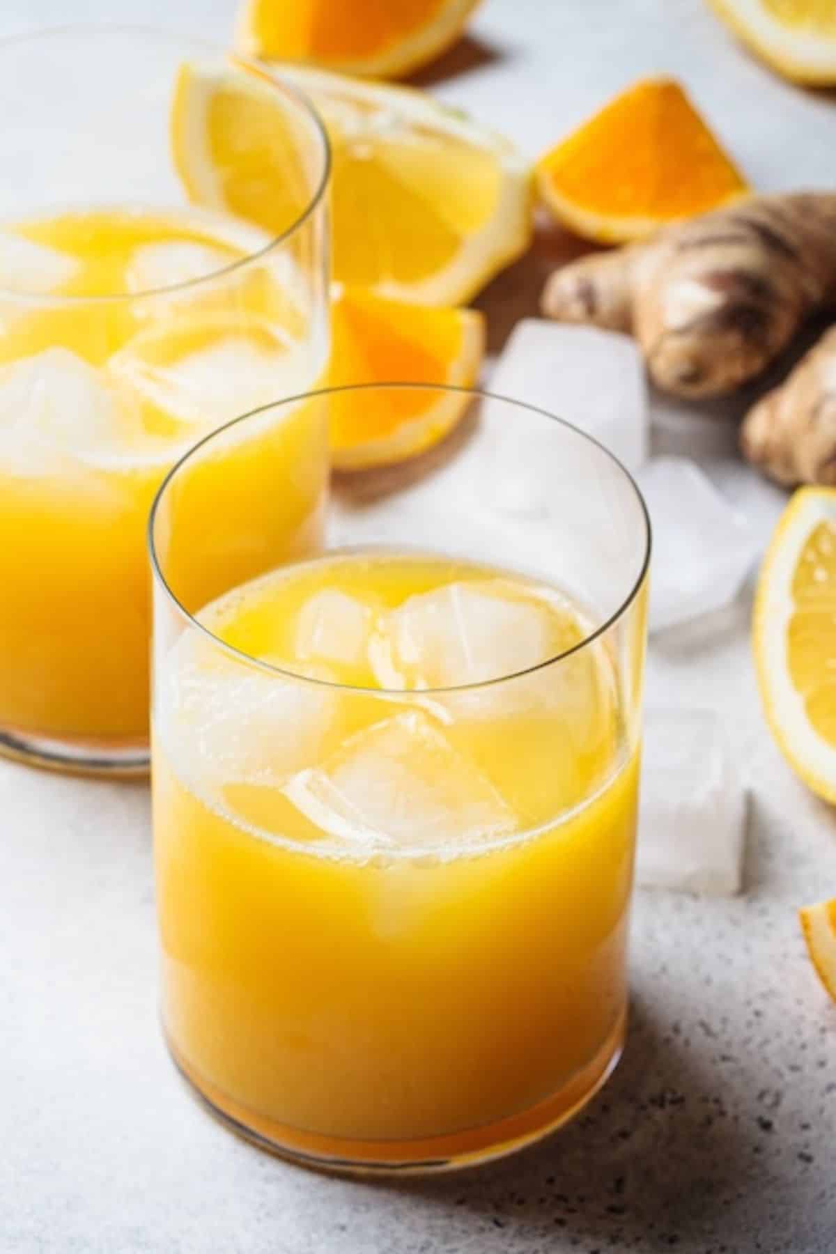 a glass of orange lemon ginger juice with ice.