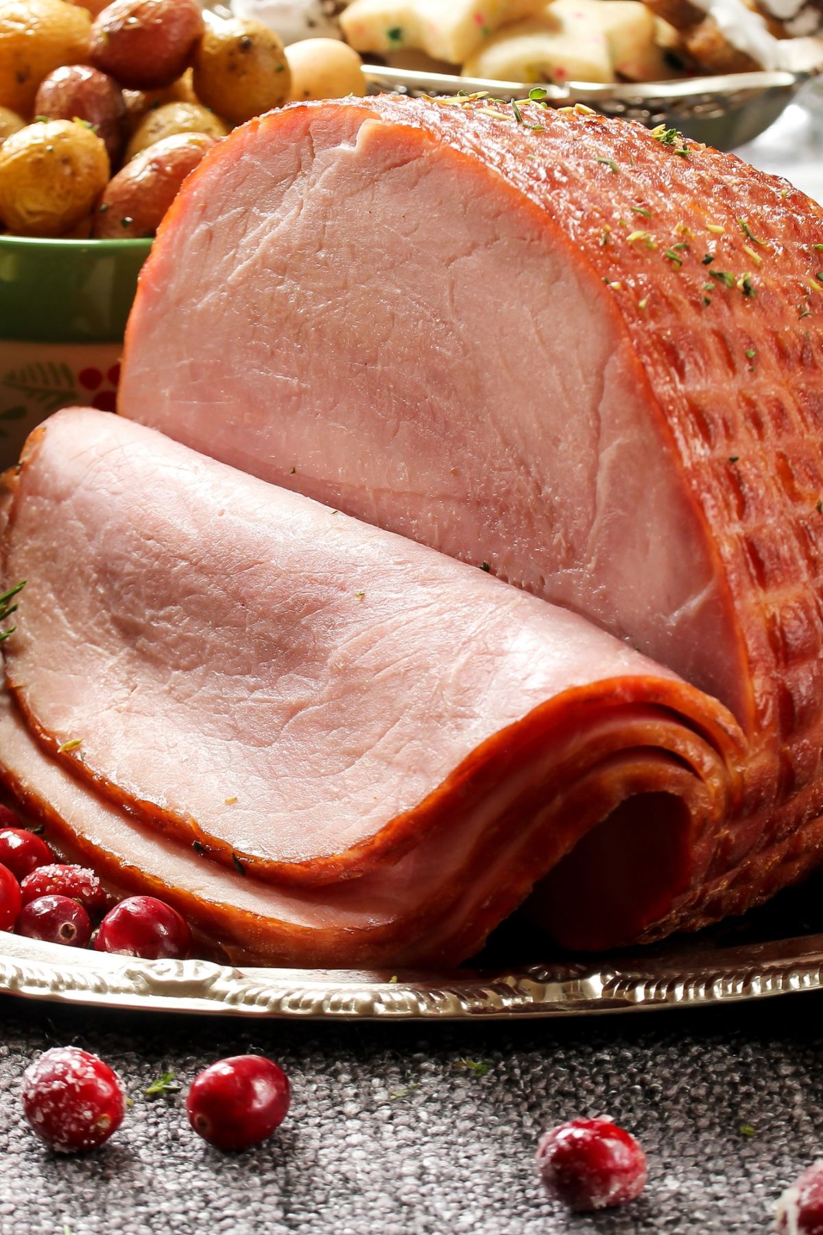 sliced ham on a table with vegetables in the background.