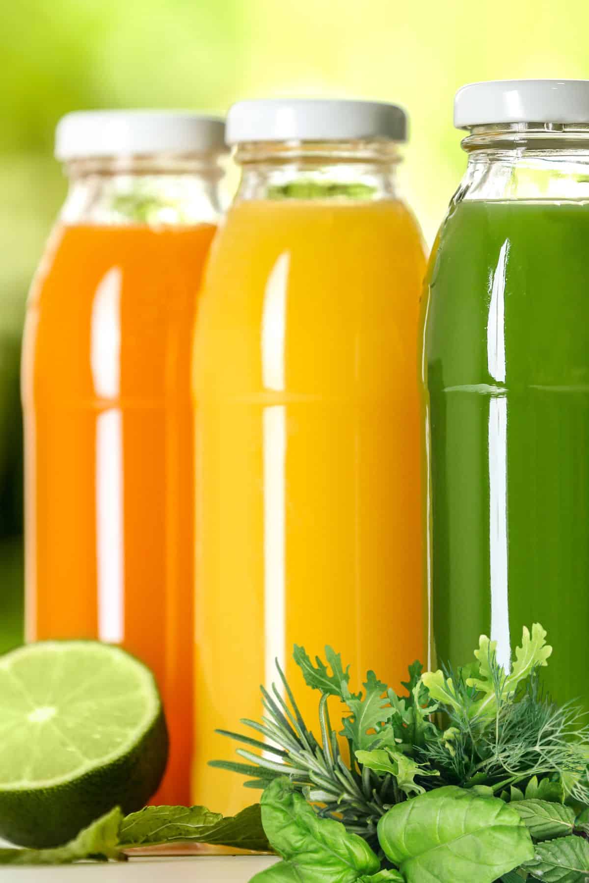 colorful juices with fresh herbs on table.