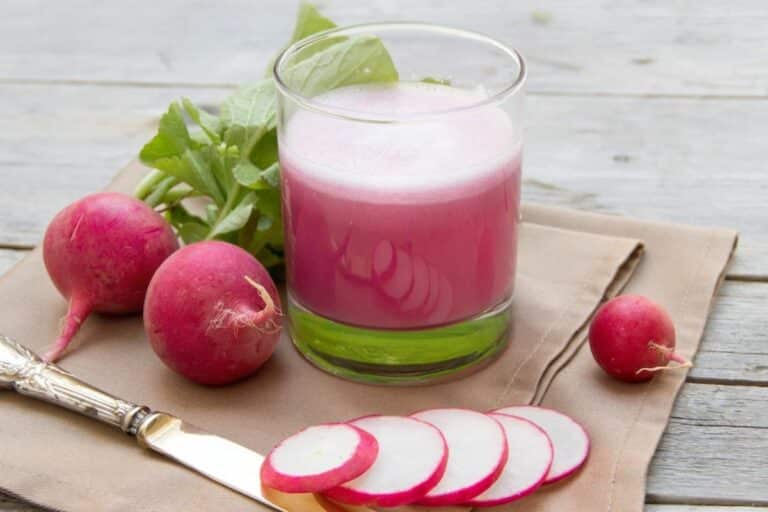 a glass of radish juice next to sliced radishes.