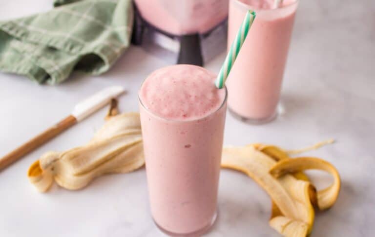 a glass of strawberry banana smoothie in a glass with a straw.