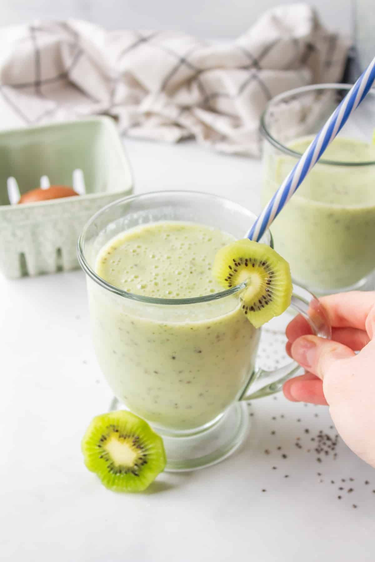 a glass of a kiwi smoothie with a straw.