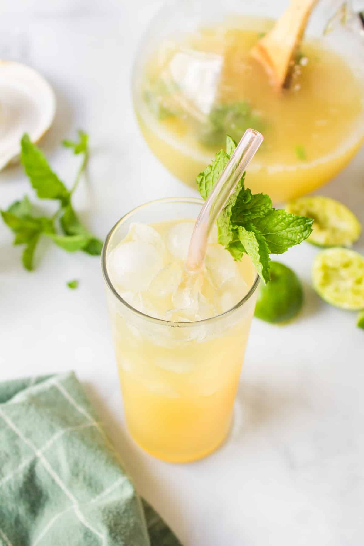 pineapple coconut water in glass with ice, mint, and straw.