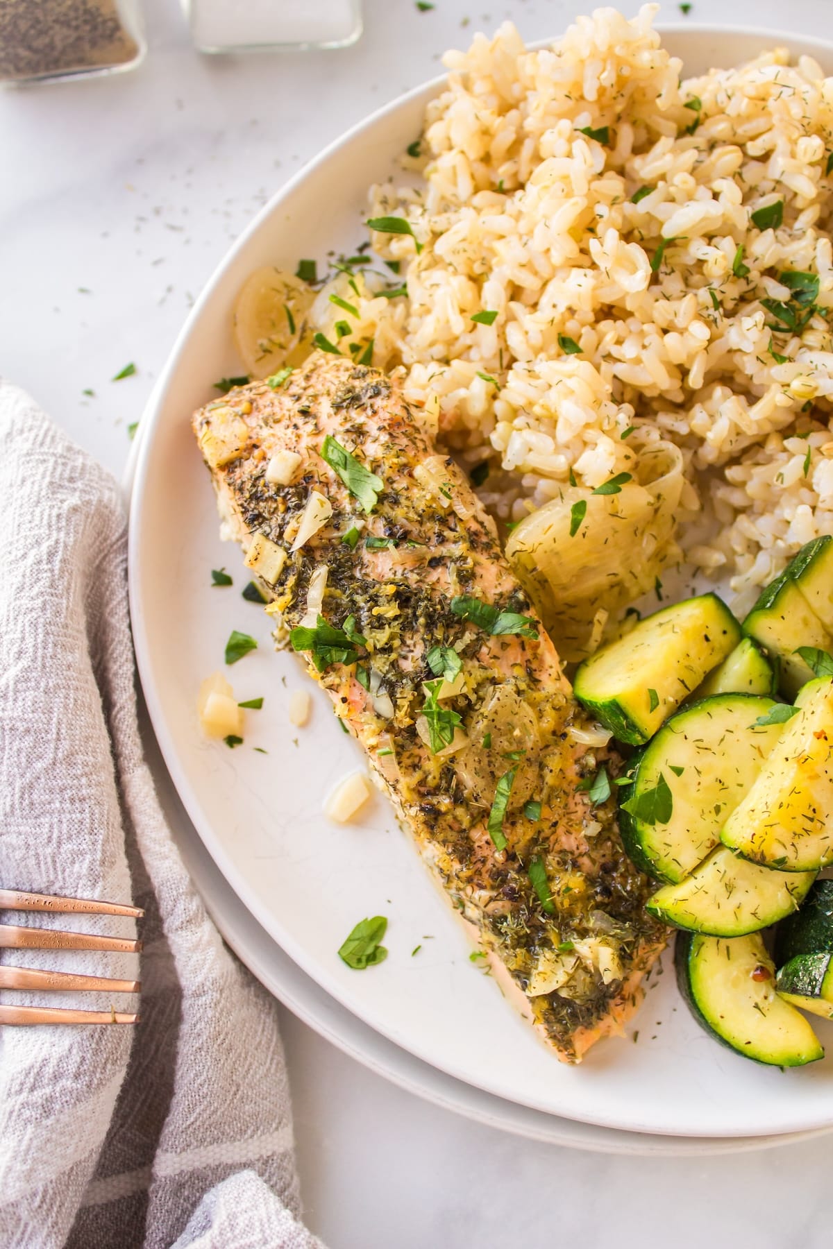 piece of cooked salmon with herbs on plate.